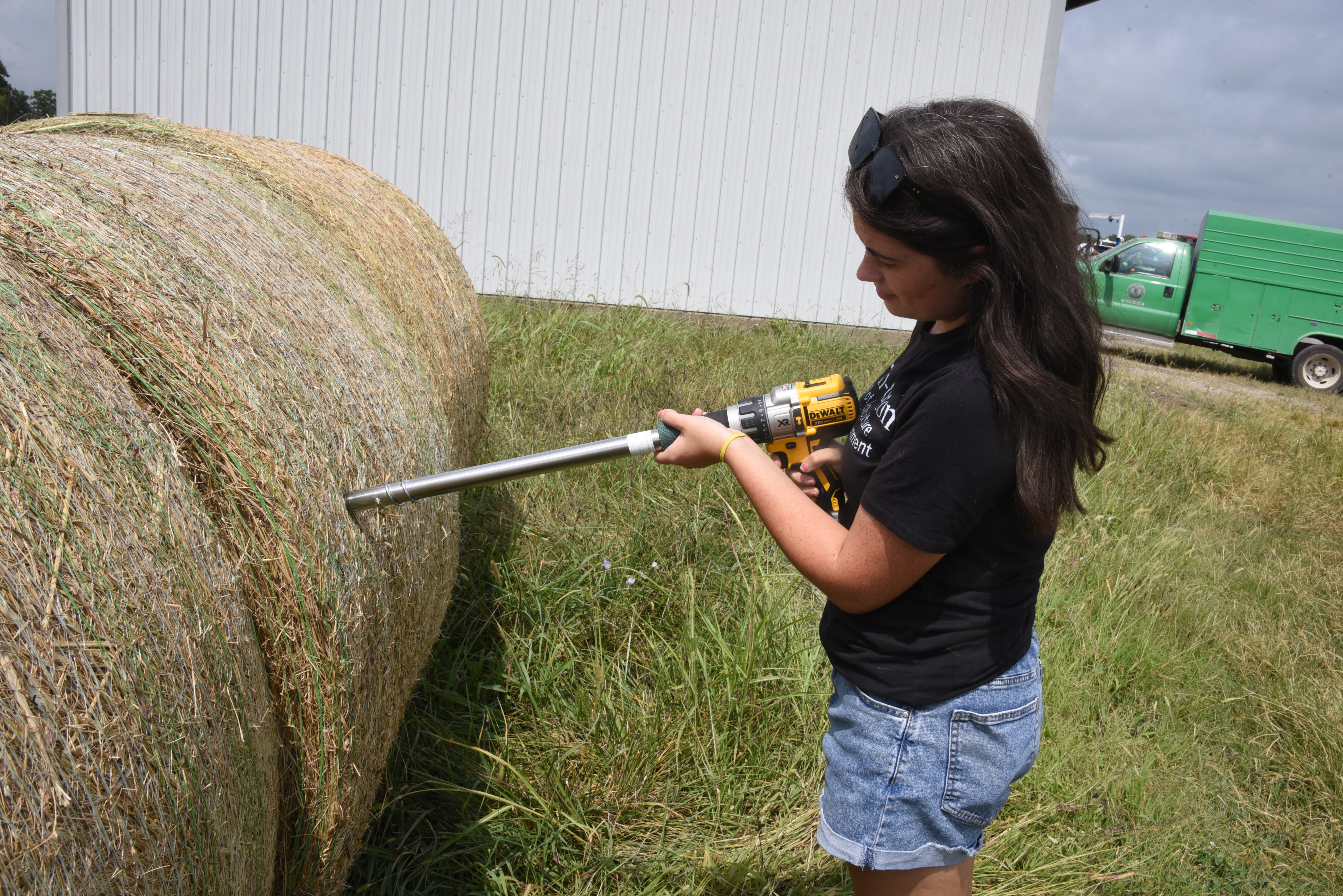 A young women works with a hay bale on a farm.